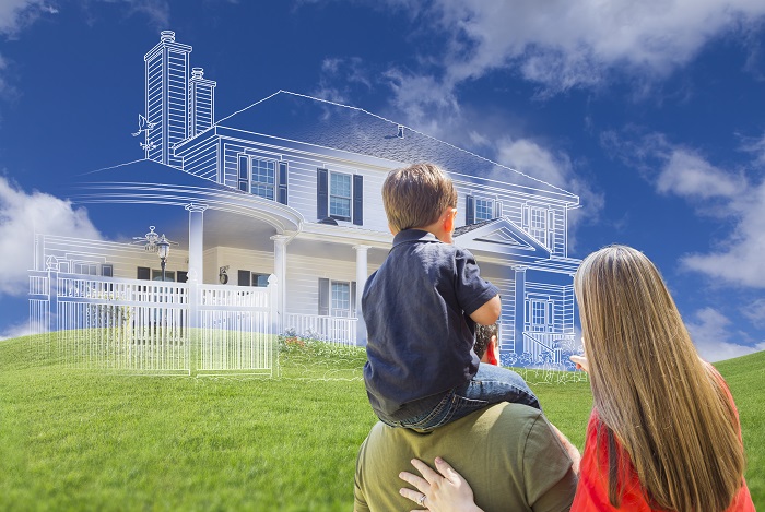 Family standing in grass looking at their proposed dream house.