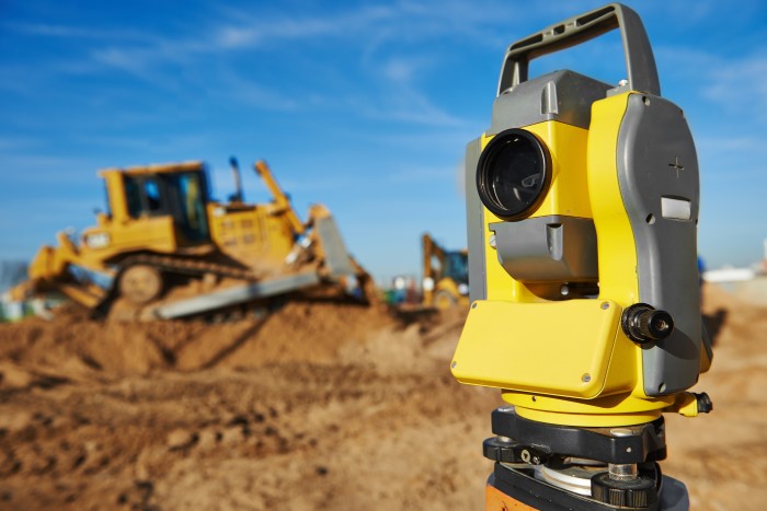 Laser in foreground and heavy equipment in the background.