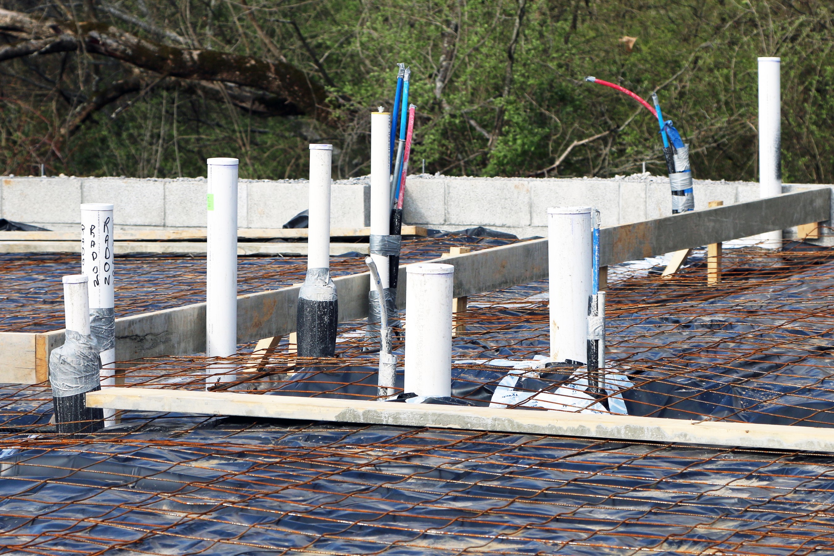 Rough in plumbing tubes above the slab concrete with rebar showing.