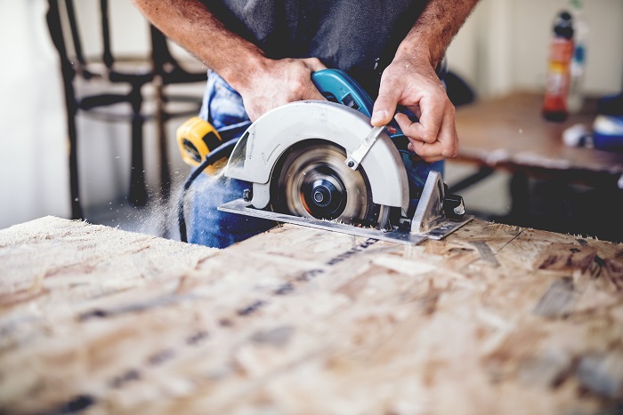 Man using electric hand saw in a workshop.