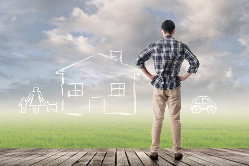 Man standing on deck looking into a field where an imaginary home is sitting.